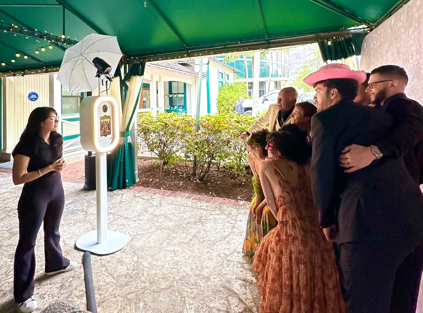 Dressed-up guests lining up at a photo booth under a tent at an outdoor party