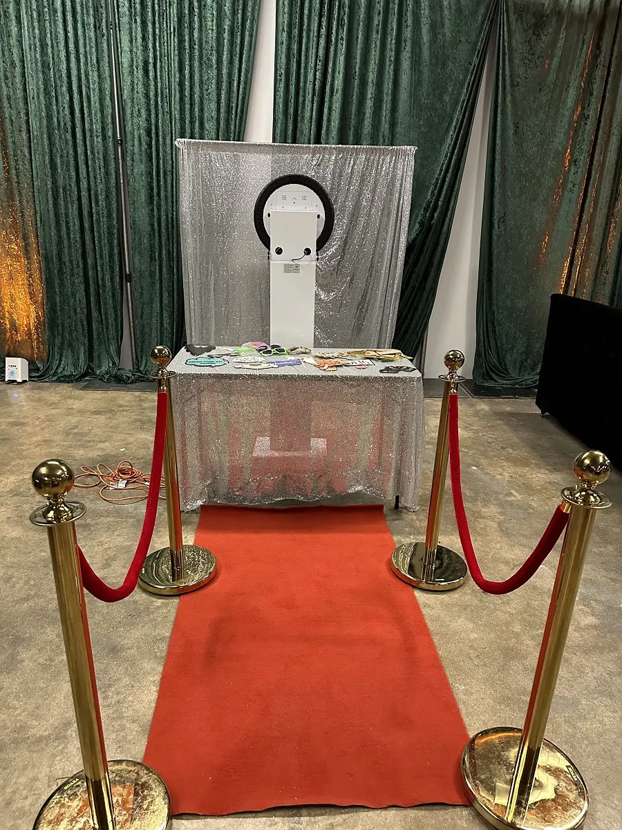 Print photo booth set up with a silver sequin backdrop, red carpet and velvet rope stanchions